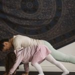 A mother and child practicing yoga together indoors, showcasing family bonding and wellness.